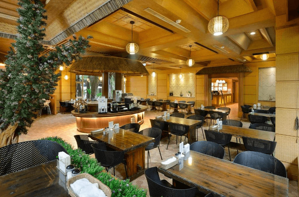 【司馬庫斯住宿】會來尖石溫泉渡假村的餐廳內部，設有多張木質餐桌與黑色座椅，空間裝飾以自然元素，如樹木造景與溫暖燈光，營造出舒適且自然的用餐氛圍。