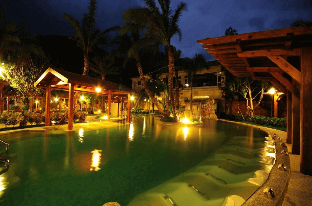 【司馬庫斯住宿】會來尖石溫泉渡假村的夜間拍攝的戶外溫泉泳池，水面倒映著溫暖的燈光，周圍環繞著熱帶植物與木質涼亭，環境浪漫且適合放鬆休息。