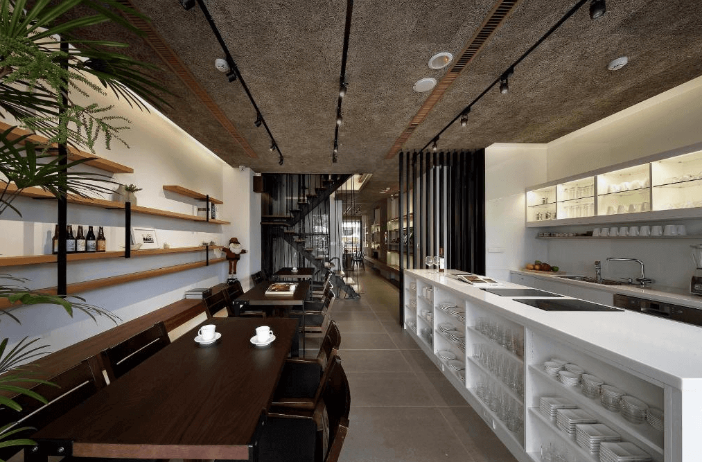 【日月潭住宿】桂月村的餐廳設計以簡約工業風格為主，使用開放式架子陳列裝飾與擺設物品。空間以原木材質搭配深色家具，天花板採用粗糙混凝土質感，營造自然且溫馨的用餐環境。