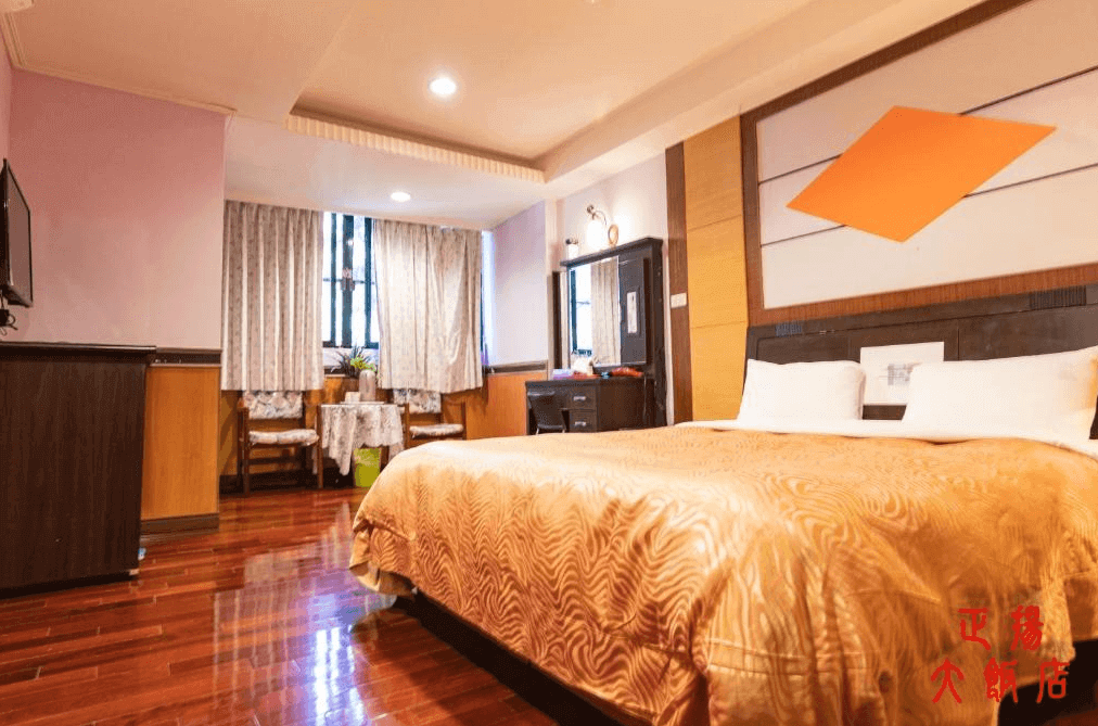 【廬山溫泉】正揚大飯店溫馨典雅的雙人房，配備大床與簡約的木質傢俱，牆面採用現代幾何裝飾，增添設計感。房內設有桌椅、化妝台與電視，整體風格融合了復古與現代元素，提供舒適的住宿環境。