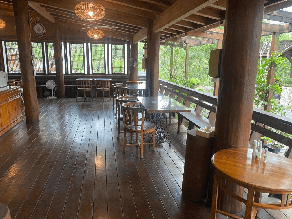 【埔里住宿】水月山莊的戶外木製用餐區，地板與桌椅皆為木材，設有長椅與圓桌，周圍被自然景觀圍繞，提供悠閒的用餐空間，適合放鬆與欣賞環境。