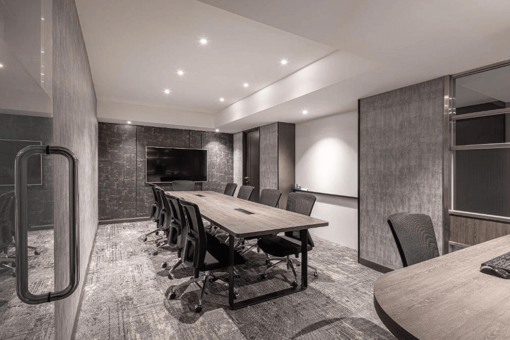 【新竹火車站住宿】煙波大飯店 新竹都會館的會議室內設有長桌與多張辦公椅，牆面以深灰色裝飾，展現專業與高雅的風格。房間內配備大尺寸電視與柔和的燈光，適合各類商務會議或簡報使用。