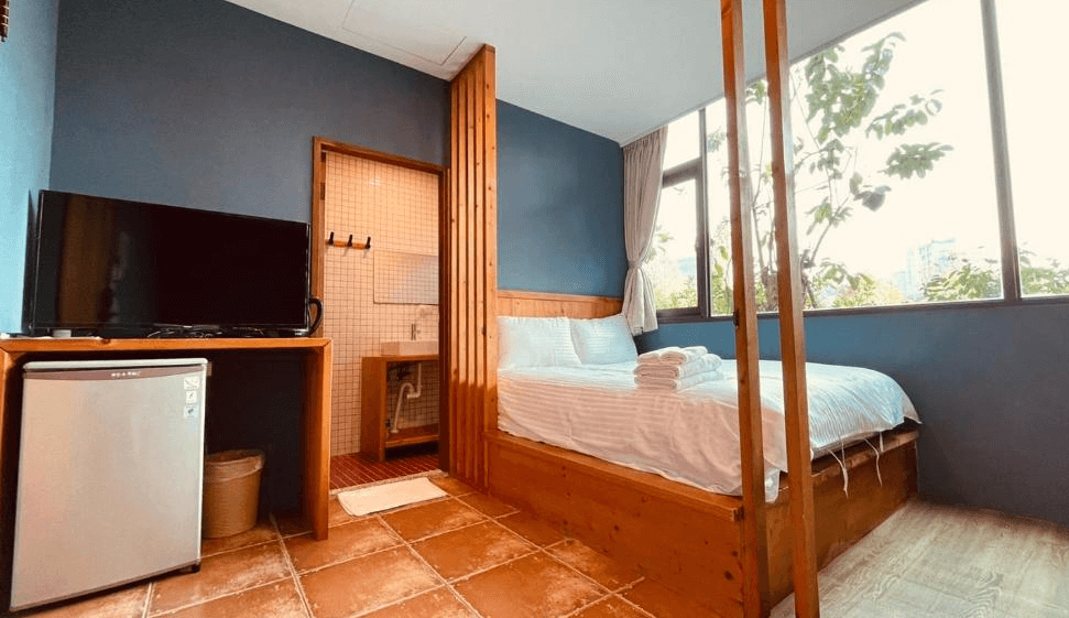 【日月潭住宿】玥湖背包客讚民宿的房間以簡約木質風格為主，空間規劃實用，內設小型冰箱、電視與獨立衛浴。大片窗戶帶來明亮的光線，讓空間更加開闊，適合喜愛簡單溫馨環境的旅客。