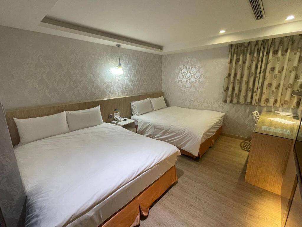 【寧夏夜市住宿】瑾旅南西館的雙人房，配有兩張大雙人床，房間裝潢以米色和灰色牆紙為主，燈光柔和，地板為木質設計，帶來舒適的氛圍。