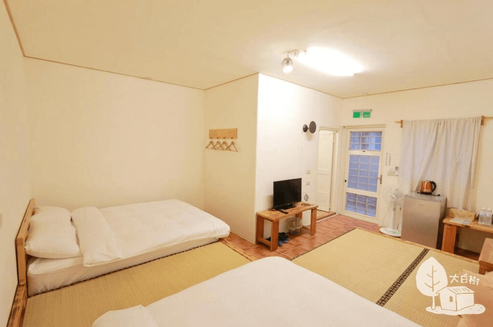 【嘉義寵物友善住宿】竹崎白樹腳驛棧的日式風格的房間，鋪設榻榻米地板，配有兩張雙人床，房間內設有電視、小型冰箱和茶水設備，白色牆面搭配木製家具，營造溫馨舒適的氛圍。