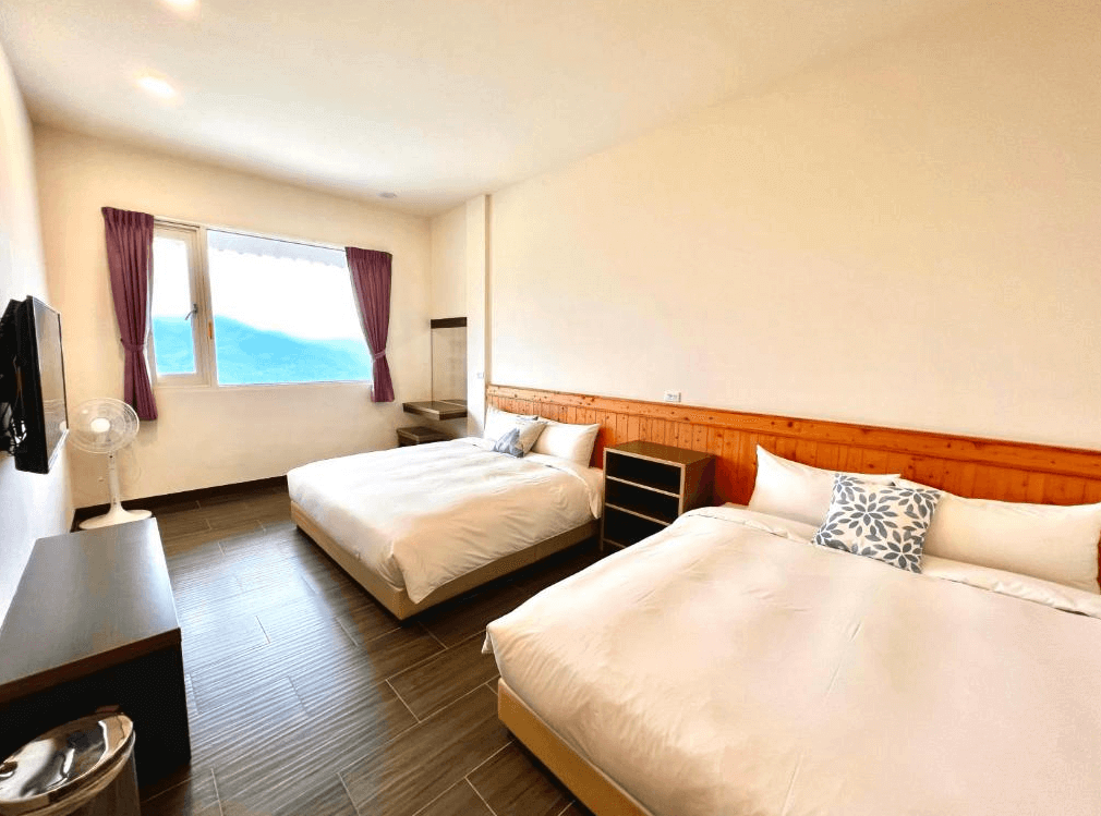 【阿里山住宿】紫龍星空民宿的客房內提供兩張舒適的雙人床，搭配明亮的大窗戶，讓住客可欣賞外面的山景。紫色窗簾與木質牆面細節，增添溫暖的住宿氛圍，適合家庭或好友入住。