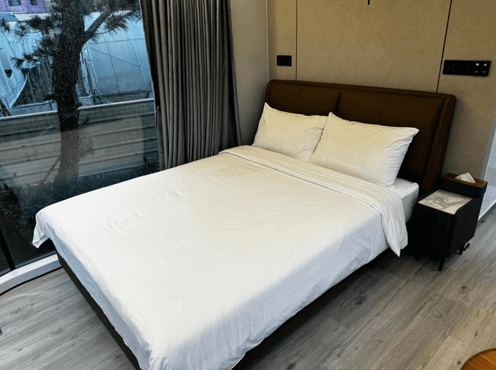 【埔里住宿】緣溪行森林營地的客房內設有一張雙人床，牆面採用柔和的米灰色調，窗外景觀清晰可見，搭配灰色窗簾，營造溫暖且私密的居住氛圍。