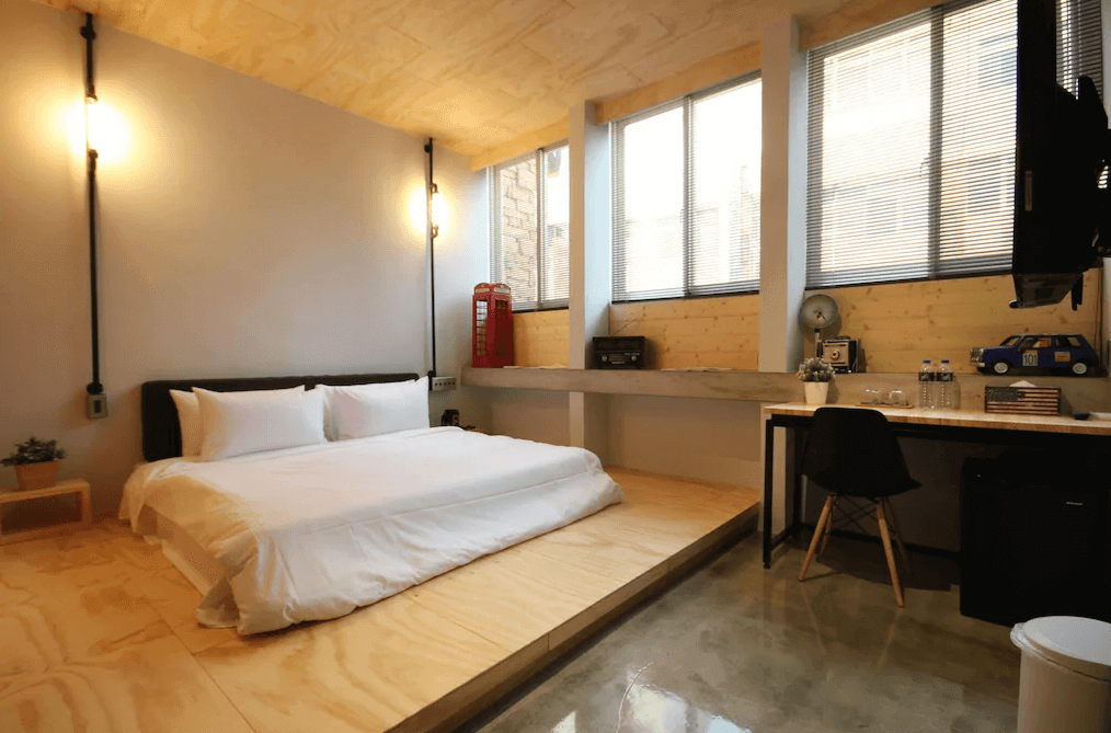 【日月潭住宿】苔米屋的房間以原木材質為主題，整體設計呈現簡約工業風格。擁有大片窗戶，光線充足，書桌及椅子位於窗邊，方便旅客使用。牆面擺放復古擺飾，為空間增添趣味。
