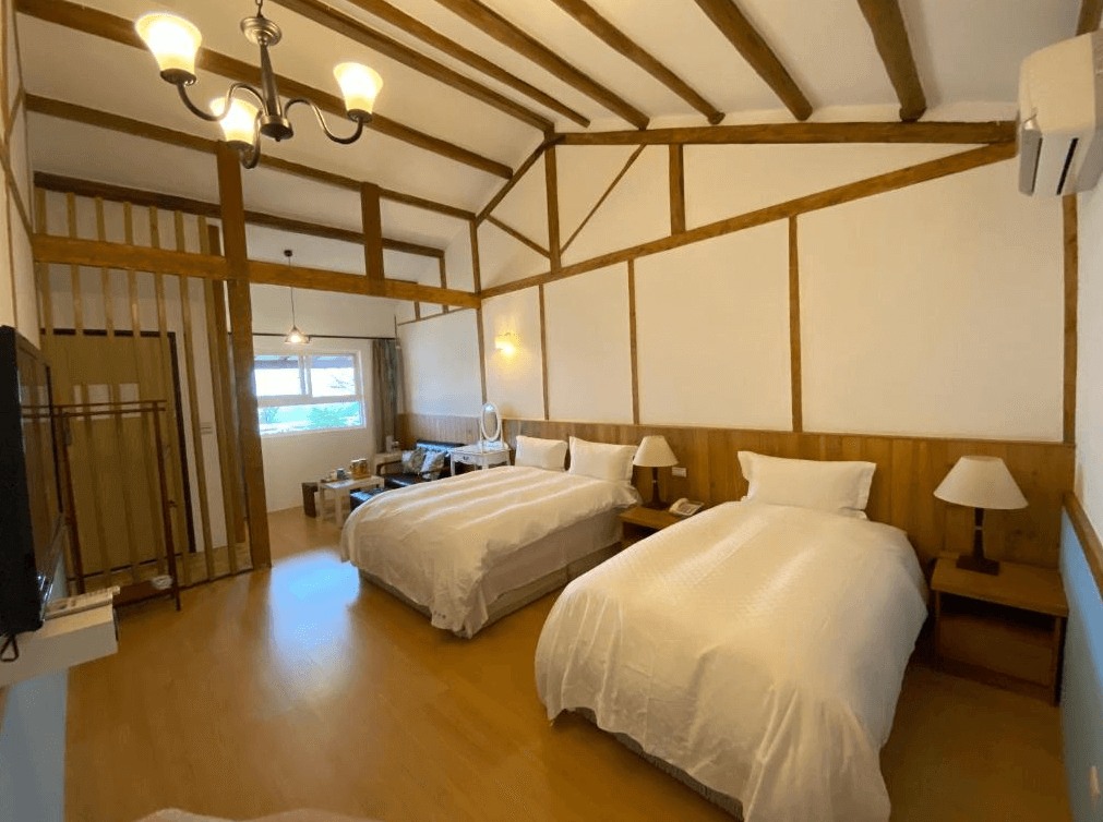 【阿里山住宿】茶香花園民宿的房內有兩張舒適的雙人床，設計以木質結構為主，天花板上可見原木樑架，散發自然溫暖的氛圍。房間寬敞，適合家庭或小團體入住。