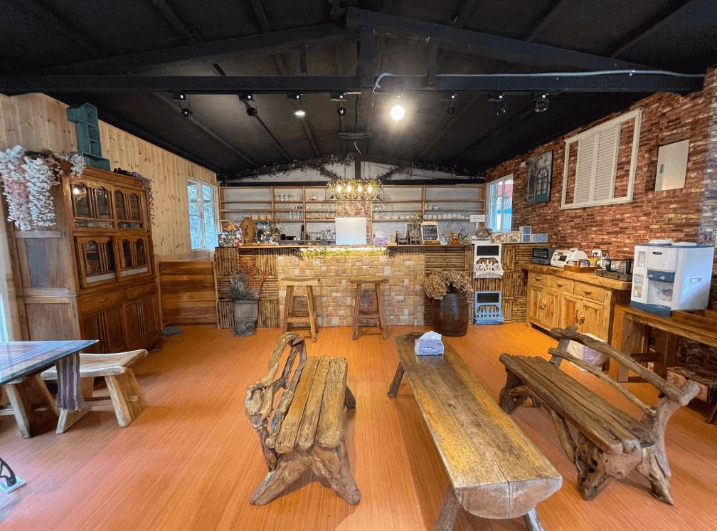 【司馬庫斯住宿】薔薇谷的鄉村風格與咖啡廳元素的室內空間，木製桌椅與裝飾散發溫馨氛圍，磚牆與木材搭配增添質樸感，櫃檯前擺放鮮花與木桶，營造出親切的聚會場所。