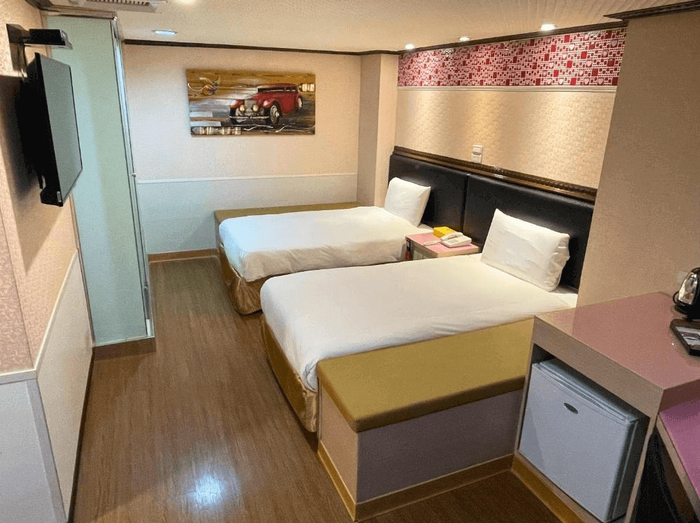 【寧夏夜市住宿】迪樂商旅的雙床房，配有兩張單人床，牆面裝飾紅色馬賽克圖案，房內設有迷你冰箱及基本家具，整體風格簡單且舒適。