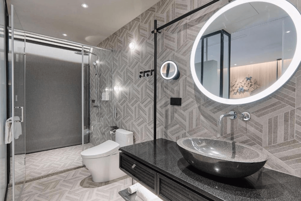 【阿里山住宿】阿里山英迪格酒店的浴室以幾何紋路瓷磚搭配現代化的設備，設計簡潔且功能齊全。圓形LED鏡面與洗手台結合，增添高雅與便利性，提供住客舒適的使用感受。