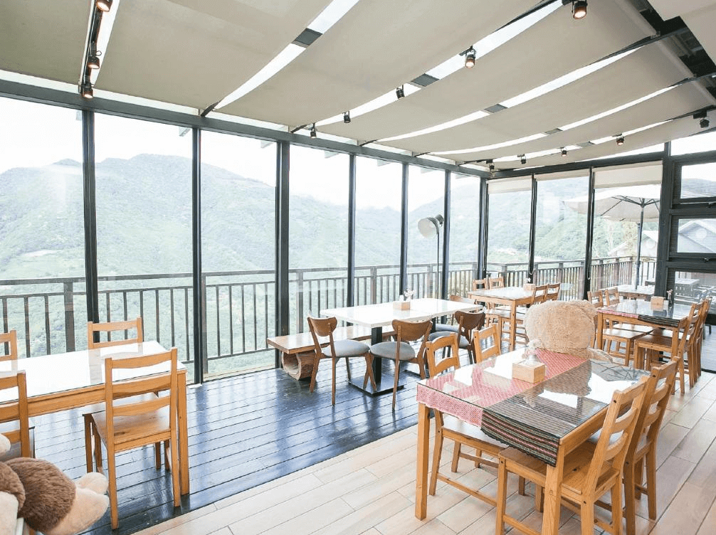 【司馬庫斯住宿】雲山房的觀景餐廳，內部擺放木質桌椅，外部景色為翠綠山景，採用玻璃屋頂設計，讓自然光線灑入，為用餐提供了放鬆又愜意的環境。