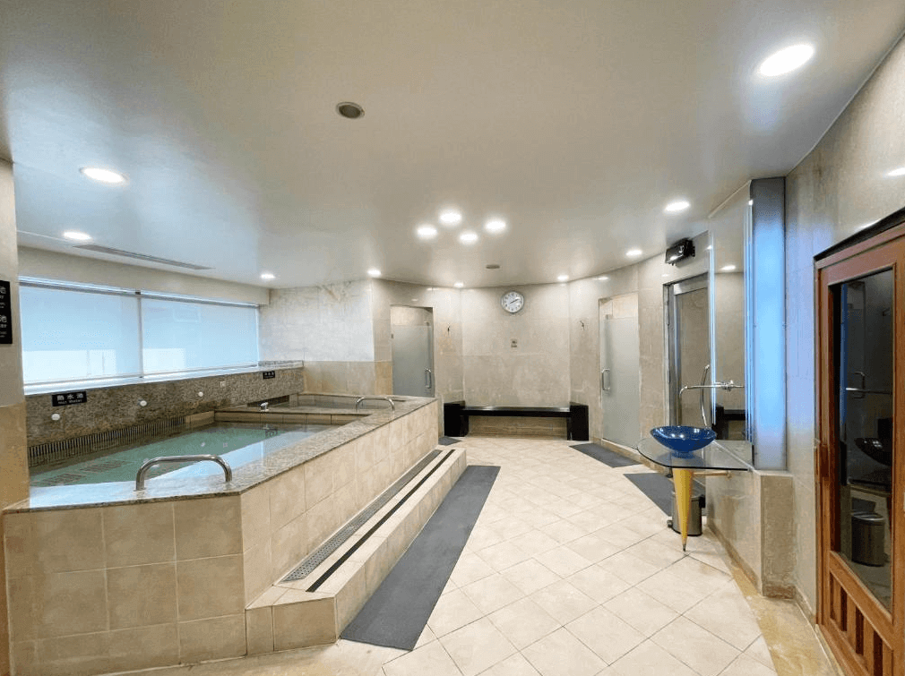 【松山機場住宿】「JR東日本大飯店台北」大浴場，設有多個溫泉池與乾濕分離的沐浴空間，整體採用高級石材與溫暖燈光設計。設有桑拿房與沖洗區，提供旅客放鬆身心的泡湯體驗。