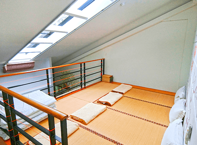 【四重溪溫泉】優生美地休閒農場的閣樓區域，鋪設日式榻榻米，可供多人席地而睡。空間設有斜屋頂與天窗，讓自然光透入，增添開放感。欄杆以黑色金屬與木質搭配，維持簡約現代感。整體設計適合親子或團體入住，感受和風氛圍。