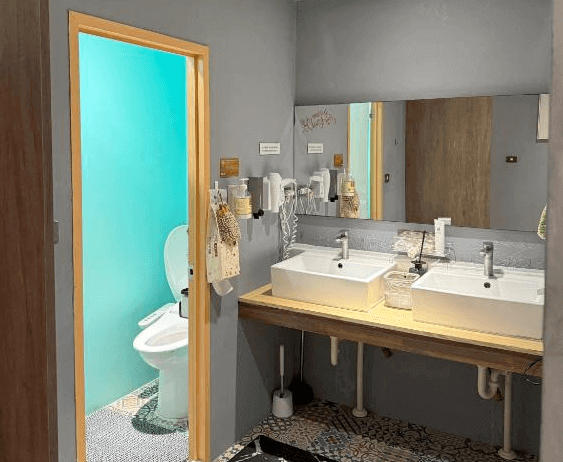 【鹿港住宿】公園一鹿背包客棧的共用浴室，浴室的洗手台設計現代，配有雙槽洗手盆和現代的水龍頭，提供了便利的設施。乾淨整潔的浴室設計簡約實用，並且配有淋浴設施和乾燥空間。