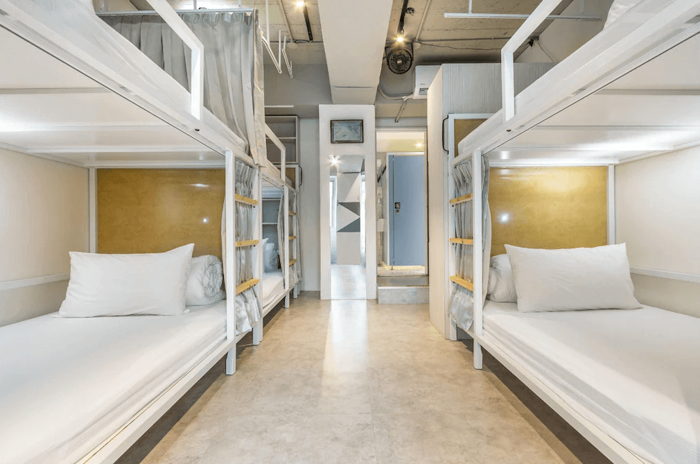 【台北車站住宿】"台北車站青年旅館"台北109青旅的宿舍房型，房內設有上下舖床位，床架為白色金屬設計，並搭配隱私遮簾與內建閱讀燈。房間採用工業風格，擁有充足的照明與開放式空間。