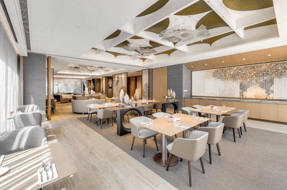 【台北車站住宿】台北中山九昱希爾頓逸林酒店的高級酒店餐廳，設有現代感十足的天花板設計與精緻燈飾。餐廳內部空間寬敞，配備木質餐桌與舒適座椅，並擺放精緻擺設，營造優雅用餐氛圍。