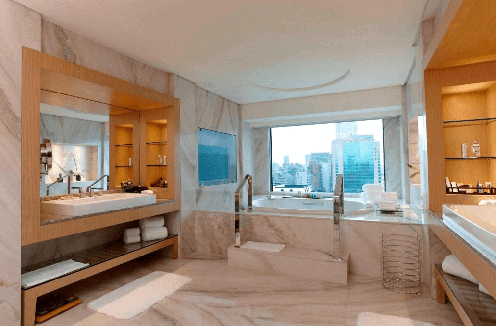 "台北親子飯店"【台北車站住宿】台北喜來登大飯店的高級大理石浴室，擁有獨立浴缸與大片落地窗，可俯瞰都市景色。浴室內配備雙洗手台、鏡面收納櫃與高級備品，整體採用大理石裝潢，展現奢華質感。