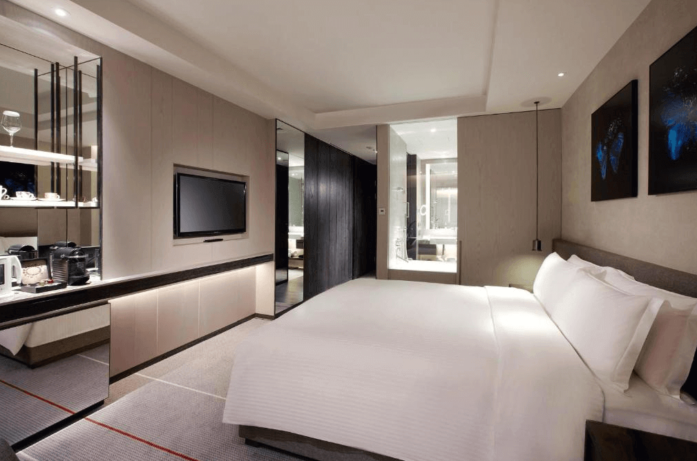 【台北親子飯店】現代感十足的台北艾麗酒店客房，設有一張舒適的雙人床，搭配柔和燈光與簡約風格的室內設計。房內備有電視、咖啡機、鏡面裝飾與開放式衣櫃，並可透過玻璃窗看到寬敞的浴室。