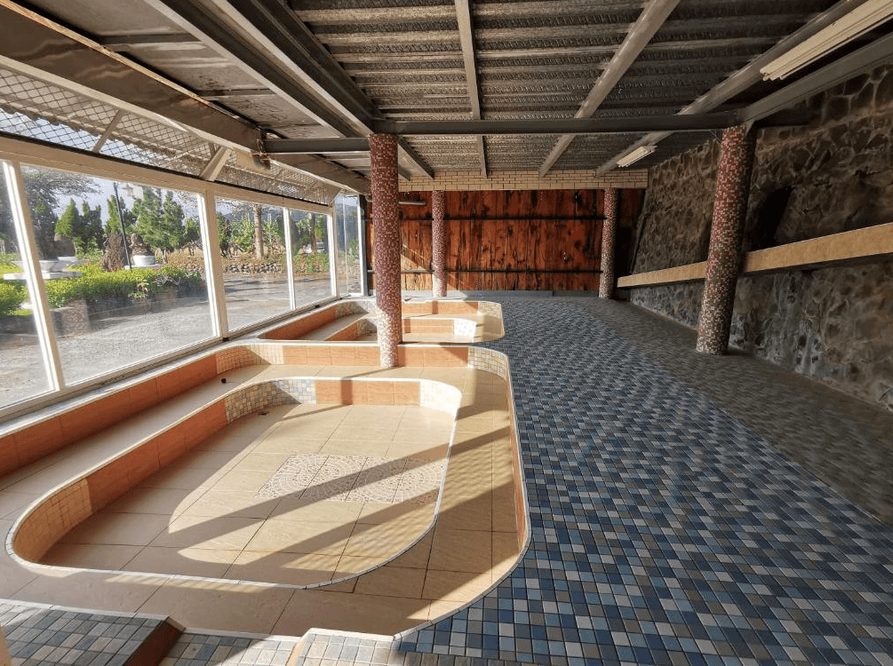 【四重溪溫泉】四重溪可以居民宿的露天溫泉區，內部鋪設藍色與米色磁磚，並設有多個浴池。空間內有大面積玻璃窗，讓自然光透入，並可欣賞戶外綠意景觀。溫泉區使用木質與石材元素裝飾，增添自然與傳統風情，是放鬆身心的理想場所。