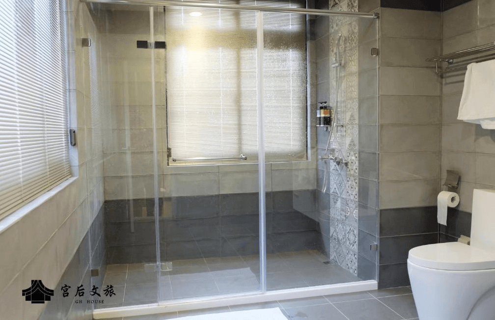 【鹿港住宿】"彰化飯店"宮后文旅的浴室，擁有寬敞的淋浴間，並使用了簡潔的玻璃隔間，讓空間顯得更加寬敞明亮。浴室內的瓷磚設計富有特色，營造出舒適的沐浴體驗。