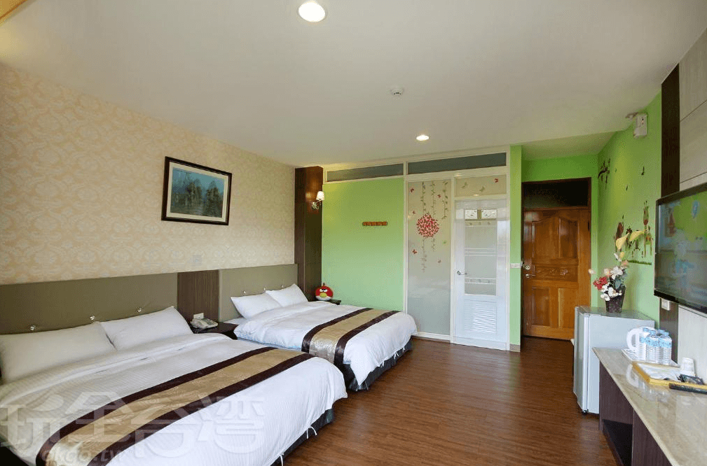 富麗渡假民宿的精緻雙床房，採用綠色與米色牆面搭配花卉裝飾，呈現自然舒適的氛圍。兩張大床鋪上質感床單，房內設有電視、冰箱及茶水設備，並有獨立衛浴，適合親子或好友出遊入住。