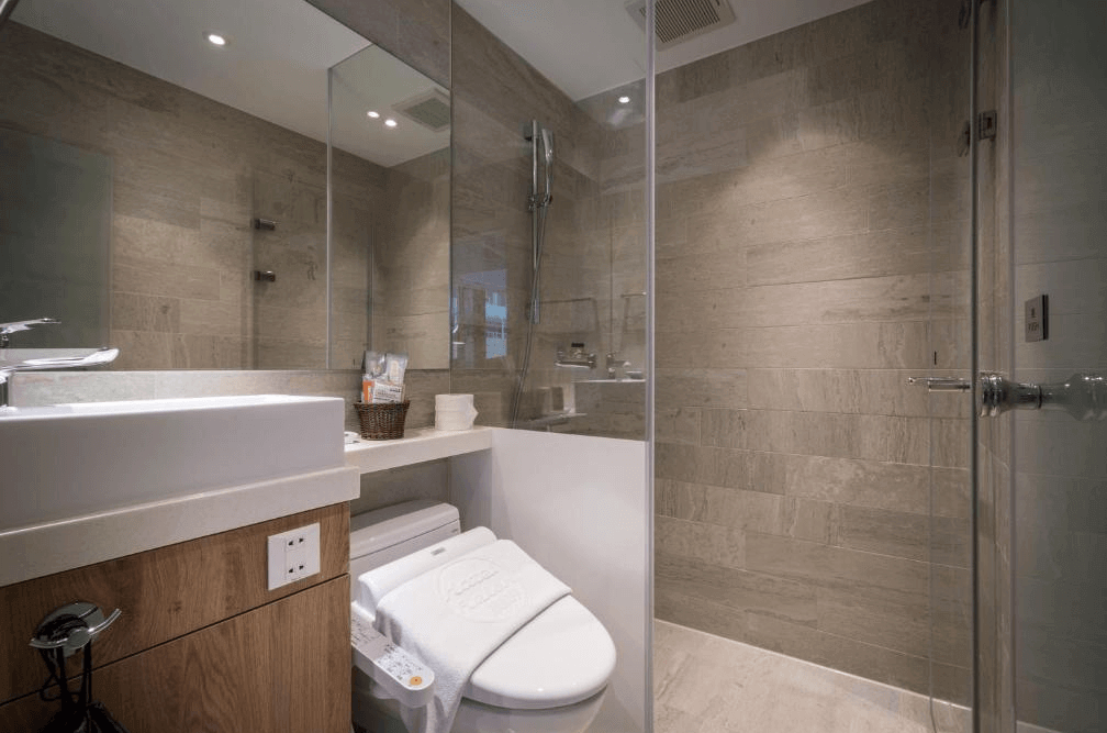 【台北車站住宿】（旅樂序精品旅館 站前五館）：時尚現代化浴室，採用大理石紋牆面與玻璃淋浴間，搭配簡約的洗手台與高級備品。空間規劃簡潔，提供舒適的沐浴體驗。