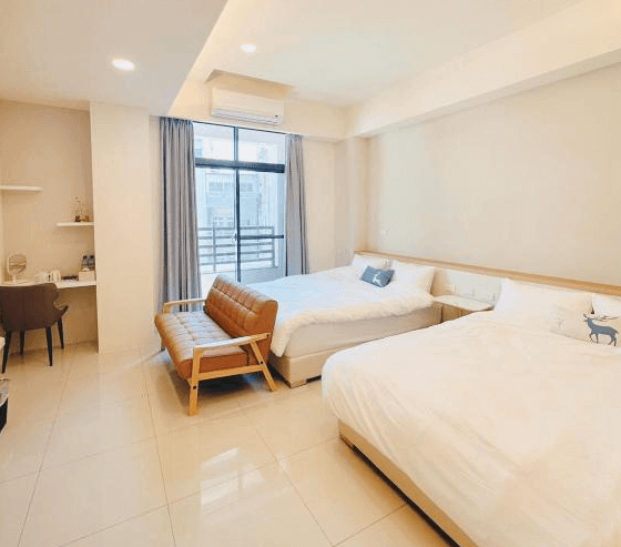 【鹿港住宿】溫怡鹿鹿WinLuLu的雙床房，簡約現代的設計風格。房間內有兩張舒適的大床，搭配簡單的沙發椅，讓整個空間感覺寬敞且放鬆。房間的窗戶讓自然光充滿整個空間，帶來清新舒適的氛圍。