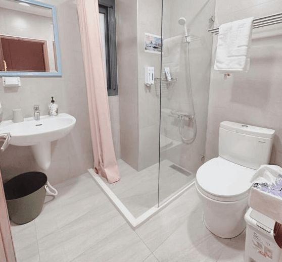 【鹿港住宿】溫怡鹿鹿WinLuLu的浴室，淋浴間的設計簡潔而實用，配有透明玻璃隔板，提供舒適的沐浴空間。白色和灰色的調色使浴室顯得清新明亮，細節處理上也十分精緻，讓人感受到便利與舒適。