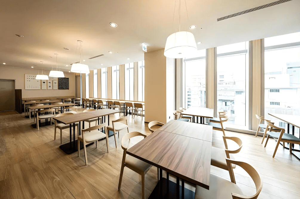 【西門町住宿】索拉利亞西鐵飯店台北西門的餐廳，空間寬敞明亮，擁有落地窗，可享受良好的自然光線與市景。餐廳內部裝潢簡約時尚，採用木質桌椅與溫暖色調的燈飾，桌椅擺放整齊，營造舒適且適合用餐的環境。