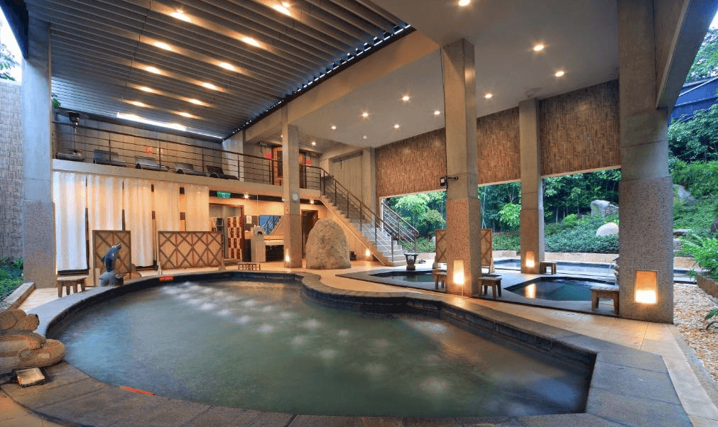 【金山溫泉】金湧泉SPA溫泉會館的戶外溫泉SPA池區，設有多個泡湯池，結合開放式設計與綠意盎然的庭園景觀。挑高屋頂與柔和燈光，營造出寧靜的泡湯氛圍，讓旅客能夠放鬆身心，享受悠閒時光。