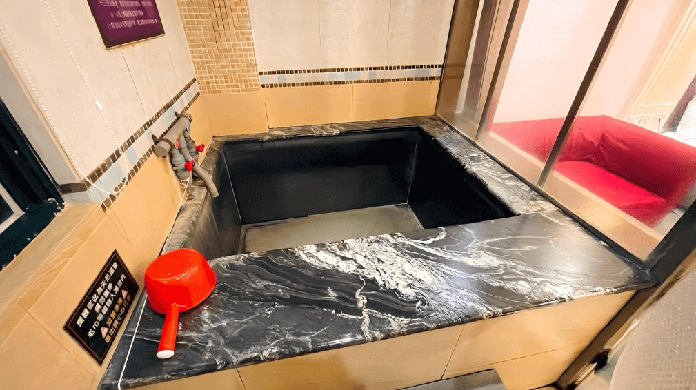 【金山溫泉】金湧泉溫泉汽車旅館大理石設計的私人湯屋，泡湯池採用黑色石材，搭配米白色磁磚牆面，整體風格典雅且質感十足。房內設有獨立熱水與冷水調節設備，並附設玻璃窗，可欣賞房間內部景觀。