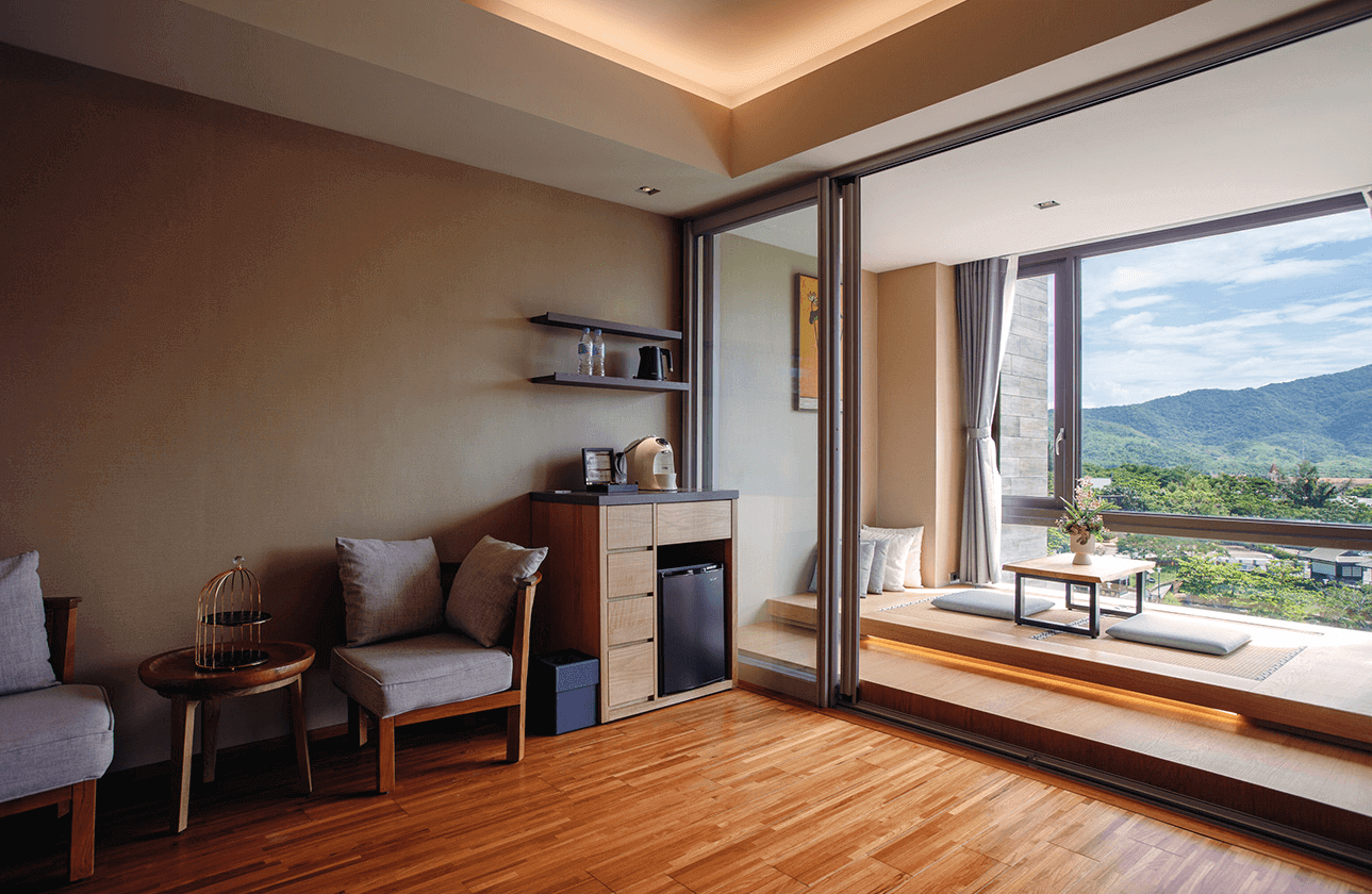 【四重溪溫泉】長鈺溫泉飯店客房內的休憩區設有木質家具與舒適座椅，搭配半開放式景觀窗，可俯瞰山景。陽台區域規劃為和式榻榻米空間，設有矮桌與坐墊，適合放鬆與賞景。