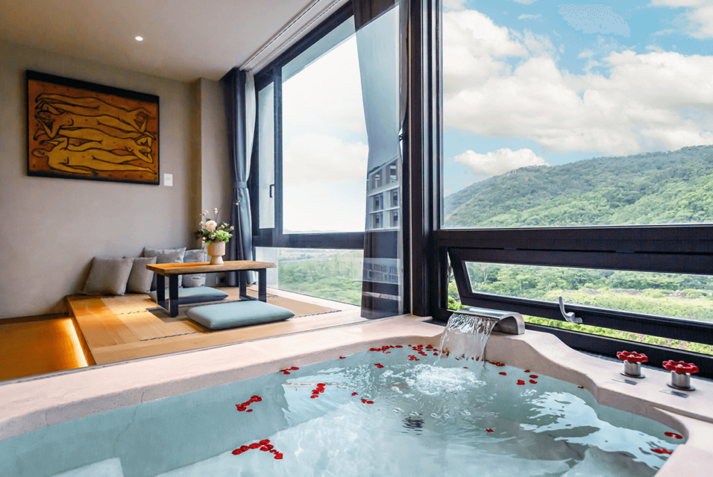 【四重溪溫泉】長鈺溫泉飯店的特色溫泉客房，內設獨立溫泉池，水流平穩且灑滿玫瑰花瓣，展現浪漫氣息。溫泉池旁為日式榻榻米區域，搭配茶几與坐墊，窗外可欣賞群山環繞的壯麗風景。