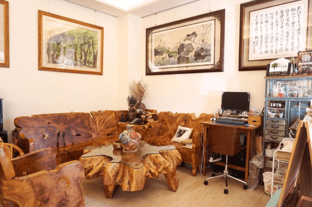 【集集火車站住宿】陶花巷弄民宿的客廳區，擺設了獨特的原木家具和裝飾畫，牆上懸掛著兩幅畫作，營造出溫暖且具藝術感的休閒空間。