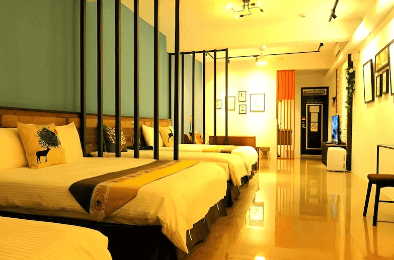 【鹿港住宿】鹿旅民宿的家庭房，這裡有三張床，並以簡約的設計風格呈現。房內有藍色牆面與黑色金屬框架床頭，這樣的設計讓整個房間看起來開闊又富有特色。溫暖的燈光與簡約的裝飾使這間房間既現代又充滿舒適感。