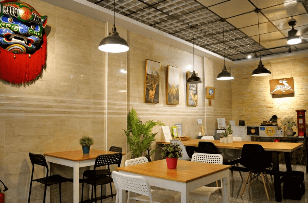 【鹿港住宿】鹿旅民宿的餐廳區域，牆上掛著具有地方特色的裝飾，包含了傳統的面具和畫作，這樣的設計增添了空間的文化氛圍。桌椅配置簡約且實用，提供了一個舒適的就餐區。