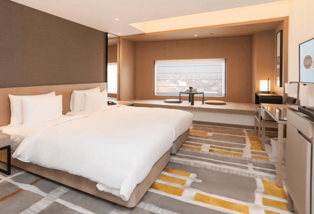 【鹿港住宿】"鹿港住宿精選圖片""彰化飯店"鹿港永樂酒店的雙床房，擁有簡約的設計風格。房內的大窗戶讓自然光透過，為空間帶來明亮的氛圍。床頭背景牆的簡單設計，搭配柔和色調的地毯，營造出一個舒適且雅緻的休息空間。