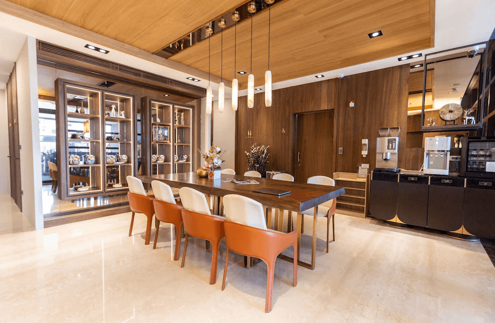 【鹿港住宿】鹿港澄悅酒店的用餐區，這裡有一張現代化的餐桌，配有優雅的座椅，增添了用餐的舒適感。背景的木質裝飾和展示櫃營造出一種精緻的氛圍，適合住客進行社交或享受輕鬆的時光。