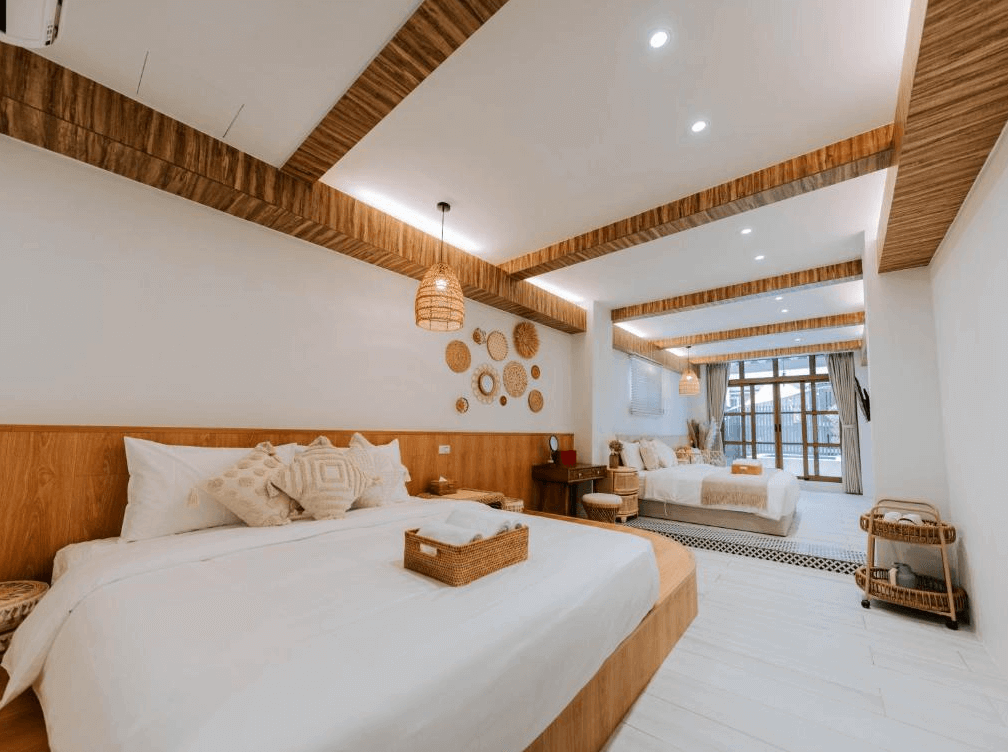 【鹿港住宿】鹿港老街十三號民宿的寬敞雙床房。自然光灑進來，營造出溫馨舒適的氛圍。房間內使用了木質和中性色調的裝飾，搭配精緻的牆面設計與圓形編織飾品，展現出現代而富有質感的設計風格。房間內的家具簡潔且實用，提供了放鬆的休憩空間。