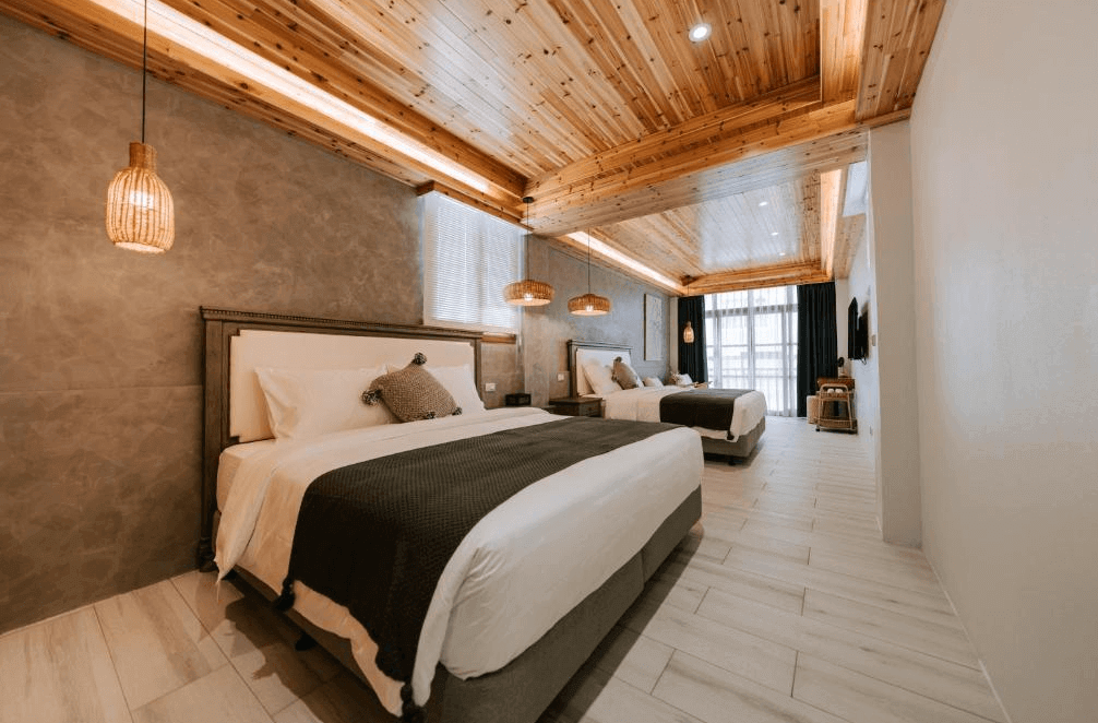 【鹿港住宿】鹿港老街十三號民宿的雙床房，這次使用了木材天花板設計，營造出更多自然感的氛圍。牆面上的燈飾與床頭板的搭配，讓整體空間更具藝術感與舒適感。大量自然光透過窗戶照射進來，使房間顯得更加寬敞與明亮。