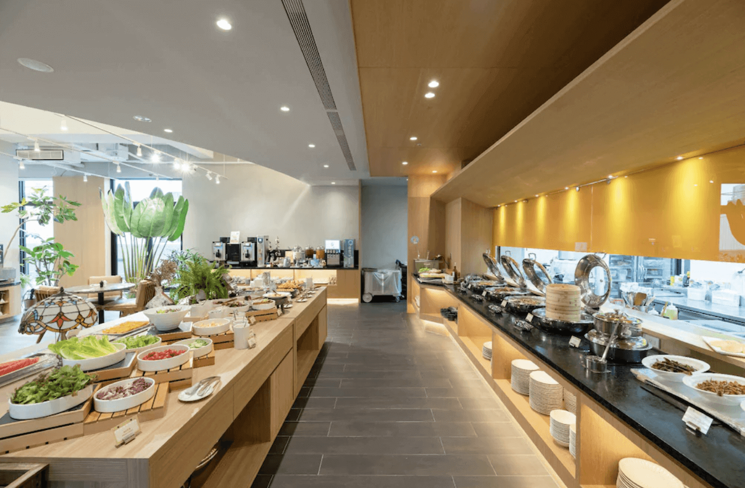 【逢甲夜市住宿】享得道行旅餐廳提供豐富的自助式早餐,空間寬敞明亮,以木質與自然植栽元素為主,餐檯上擺放著各式新鮮餐點,環境整潔舒適,營造愉快的用餐體驗。