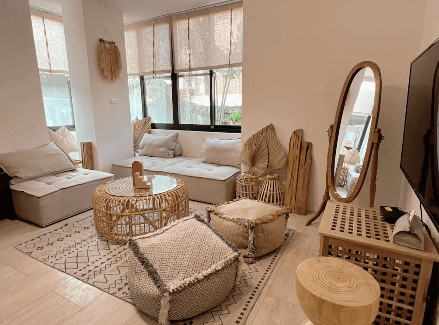 【台南安平住宿】四季洋房的客廳空間採用大量天然材質與中性色調佈置，搭配藤編茶几與懶人坐墊，牆面懸掛乾燥葉片與藝術裝飾，空間設計融合日系與波希米亞風，營造出放鬆自在的社交氛圍。