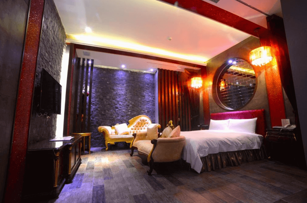 【斗六住宿】天上人間精品旅館的雙人房，牆面為仿石磚材質，搭配紫色燈光與紅色鏡面牆，床鋪旁擺放著金色與米白色的復古沙發，整體設計富有情調，營造出夜店式的摩登氛圍。