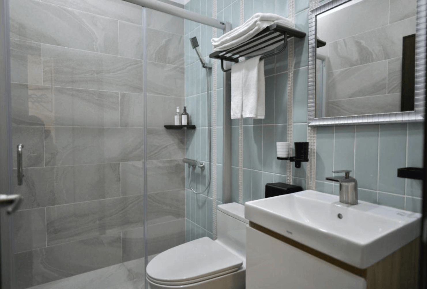 【台南安平住宿】安平有間旅店的浴室空間，採乾濕分離設計，配有淺藍色磁磚、玻璃拉門與簡潔洗手台，整體明亮清新。