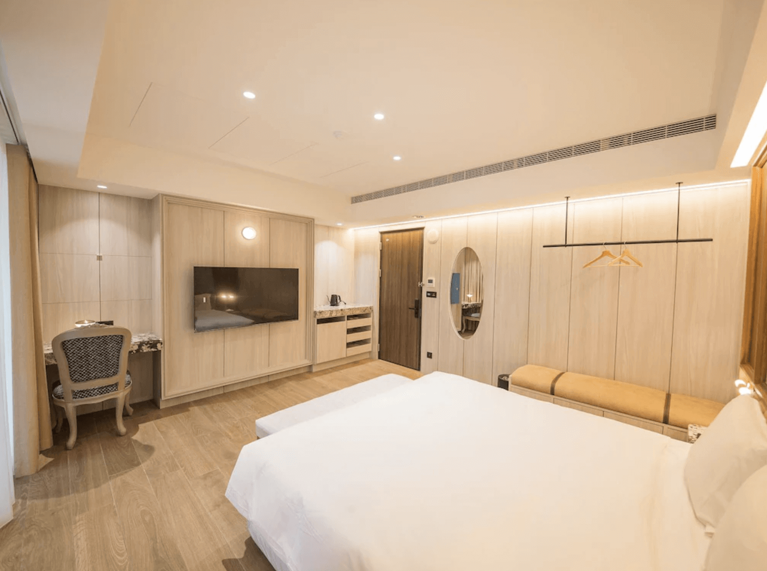 【台南安平住宿】安平留飯店溫潤木質調的雙人房，設有書桌、電視與衣架，空間寬敞明亮，搭配精緻的梳妝鏡與茶水備品，展現典雅細膩的設計風格。
