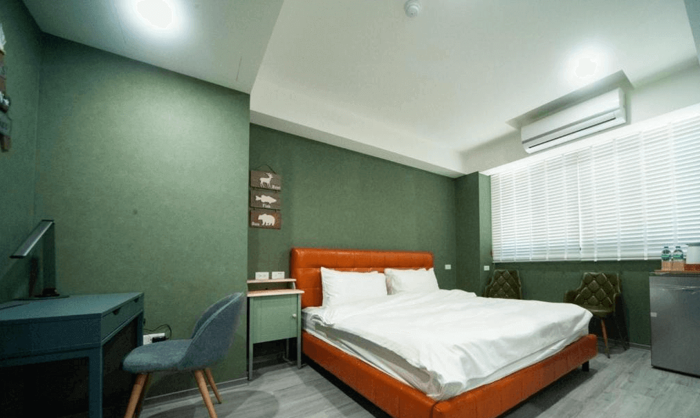 【虎尾住宿】小9窩BNB的雙人客房，搭配橘色皮革床架與白色床鋪，房內設有書桌、雙椅、空調與迷你冰箱，大面窗戶帶來明亮自然光，整體氛圍舒適溫馨。