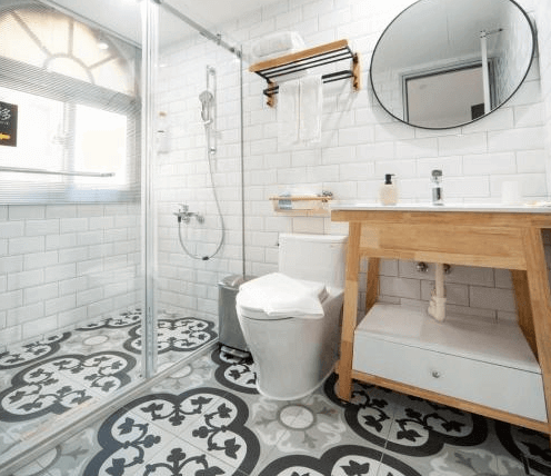 【虎尾住宿】小9窩BNB的混搭復古與現代感的浴室空間，地面為花磚設計，牆面鋪設白色磁磚，配有乾濕分離淋浴間、木質洗手台與圓形鏡子，整體整潔明亮且具設計感。