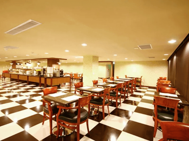 【員林住宿】康橋商旅-員林館的自助餐廳，地面採用黑白相間的棋盤格瓷磚，搭配深木色餐桌椅，展現典雅風格。空間寬敞明亮，提供豐富的自助早餐，並設有開放式取餐區，提供舒適的用餐環境。